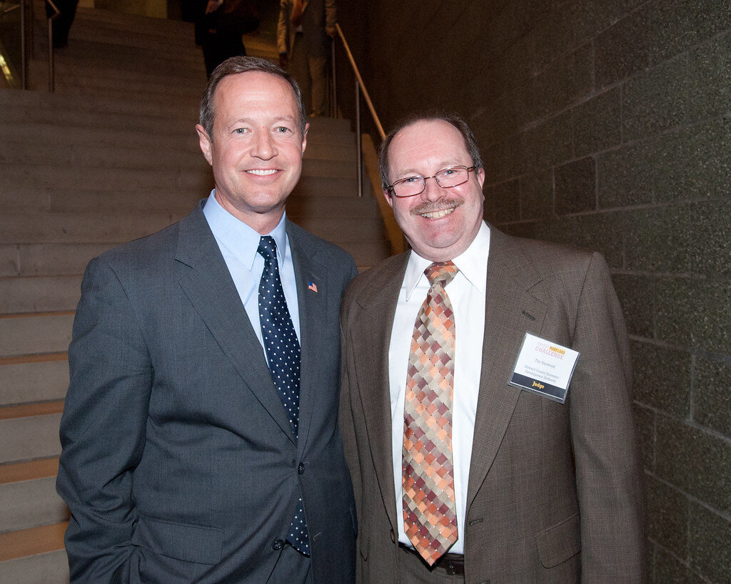 A businessman with glasses reviewing data on a tablet in an office setting.
